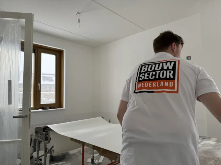 Behanger van Bouwsector Nederland met een baan vlies op de plaktafel in een lege nieuwbouwkamer