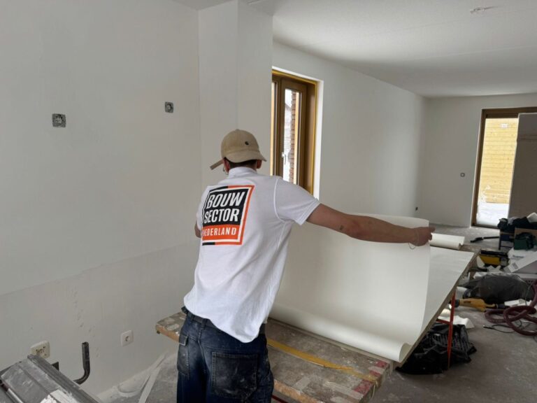 Renovlies behanger van Bouwsector Nederland rolt een baan renovlies uit op de plaktafel in een nieuwbouwwoning